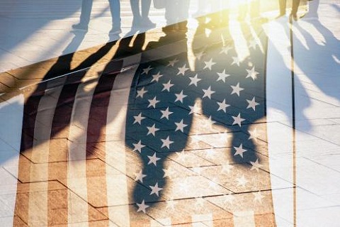 Puerta de vidrio que refleja a personas y a la bandera de USA